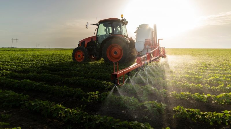 Tractor spraying pesticides on soy field  with sprayer at spring